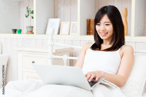 young asian woman using laptop in the bed room