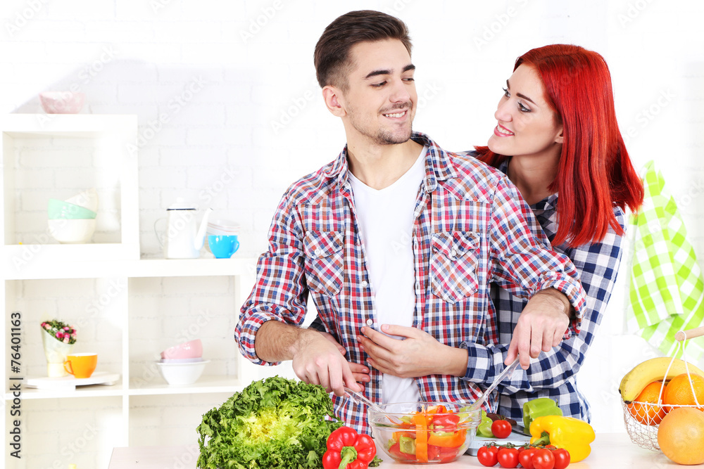 Happy couple preparing  vegetable salad in kitchen