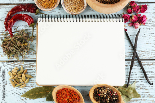 Spices with recipe book on color wooden table background photo