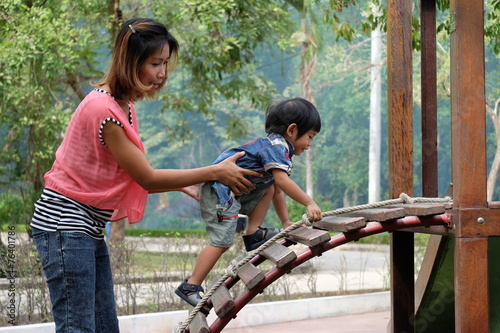 mother help her son to climp a stair with rope photo