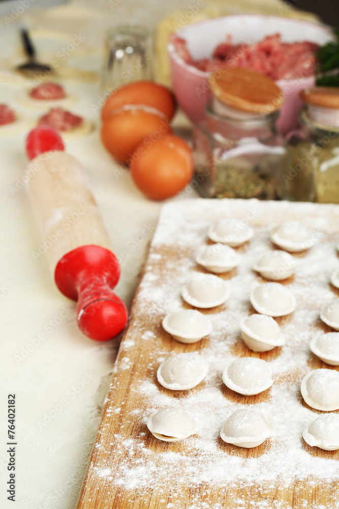 Raw dumplings on cutting board on table close-up