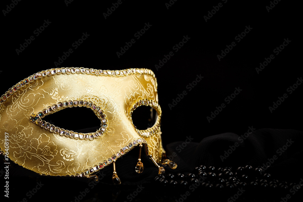 Golden mask near pearls on black