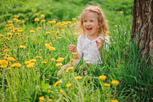 spring portrait of adorable child girl on dandelion field