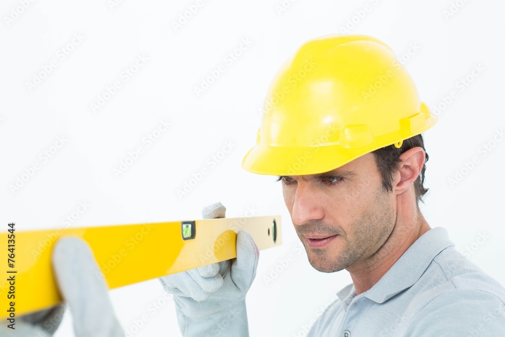 Carpenter wearing hard hat while using spirit level Carpenter wearing hard hat while using spirit level