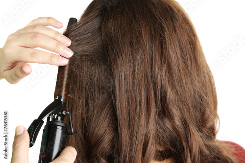 Stylist using curling iron for hair curls, close-up, isolated