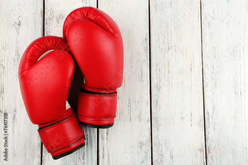 Pair of boxing gloves on color wooden background