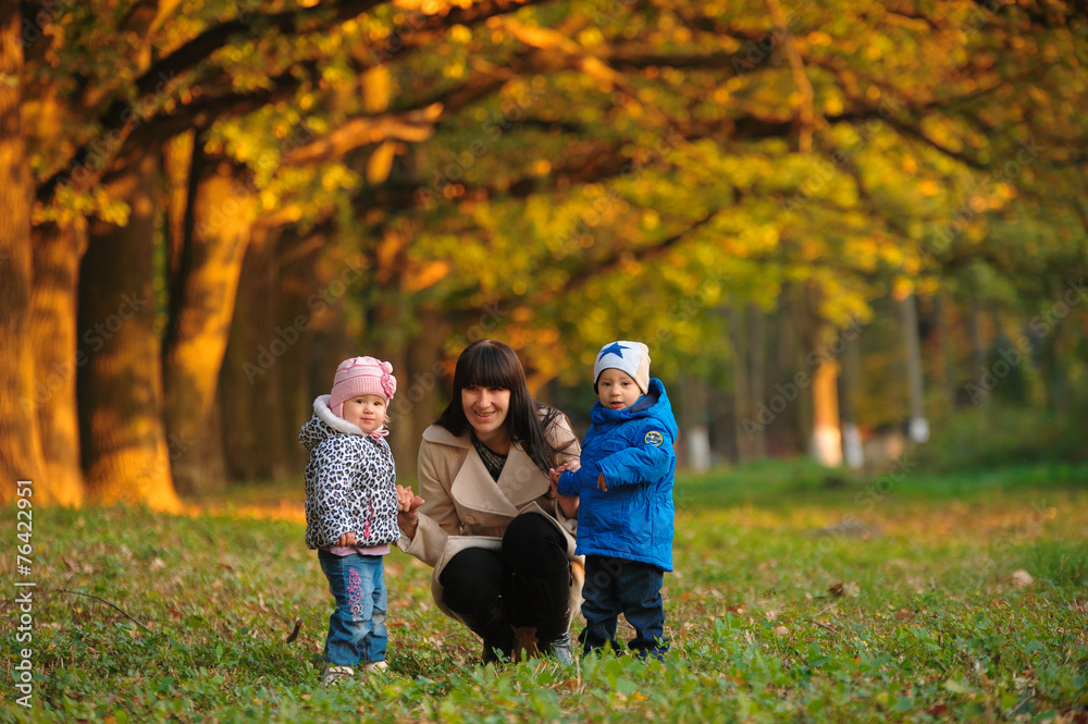 Fototapeta premium mother with children twins on a walk in the autumn park