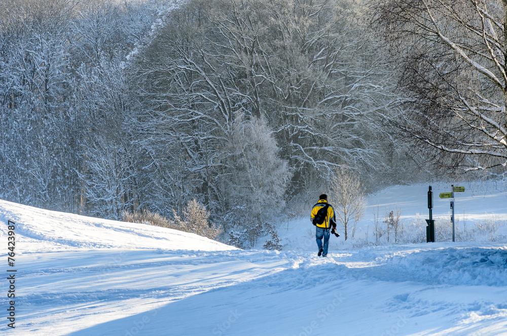 Verschneite Landschaft mit schneebeladenen Bäumen und einem Man