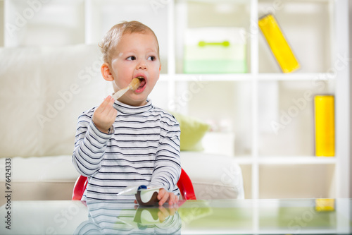 Valokuva Two-years child himself eats with spoon