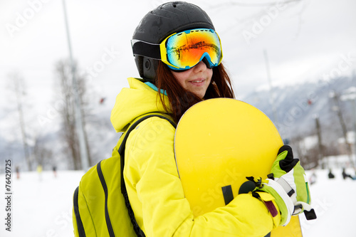 Smiling young gigl holding snowboard photo