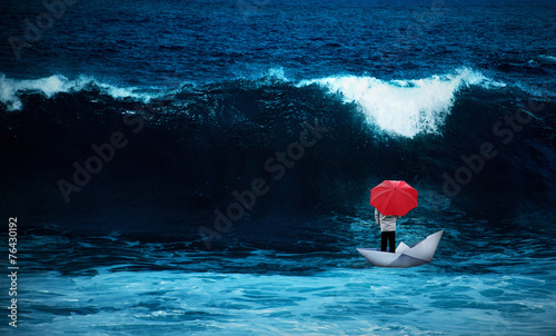 Canvas Print Man with red umbrella in a paperboat in the rough sea