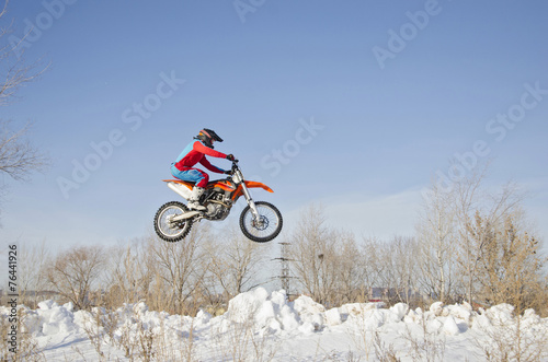 MX driver on the motorcycle is flying over the hill snow