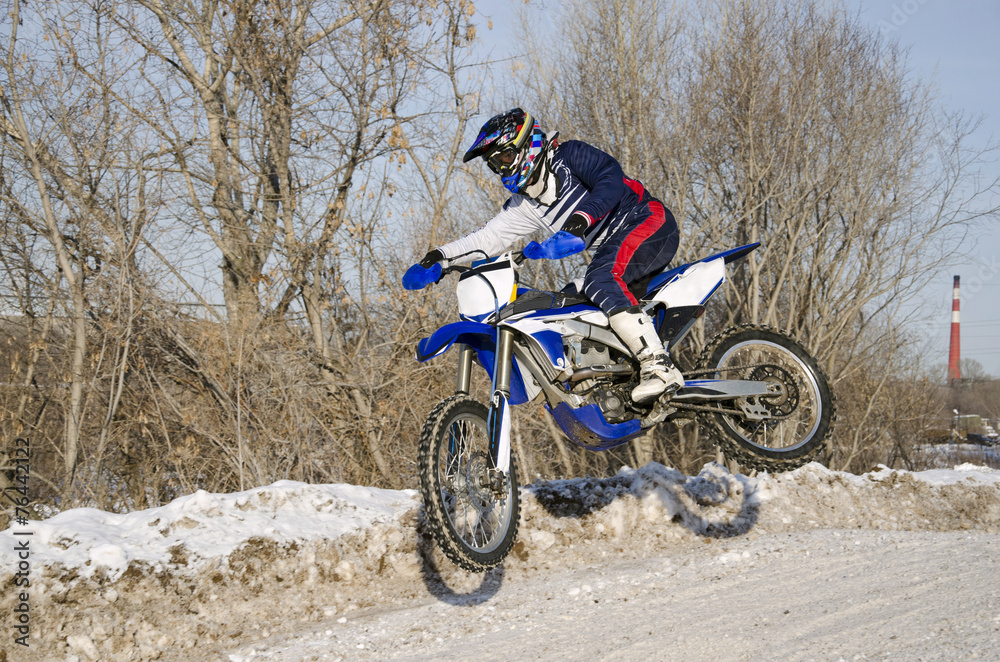 Motocross, motorcycle driver flies over hill out of snow