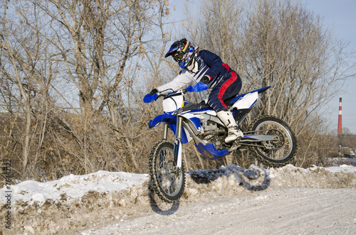 Motocross, motorcycle driver flies over hill out of snow