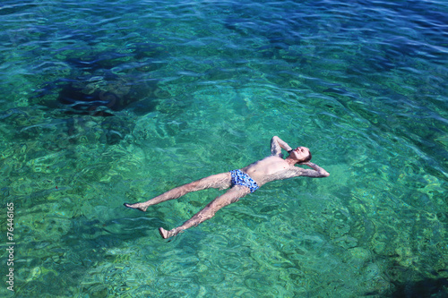 Man, relaxing in the clear sea water, lying on the water