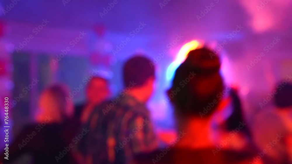 People silhouette dancing in spot light rays lumiere on a disco