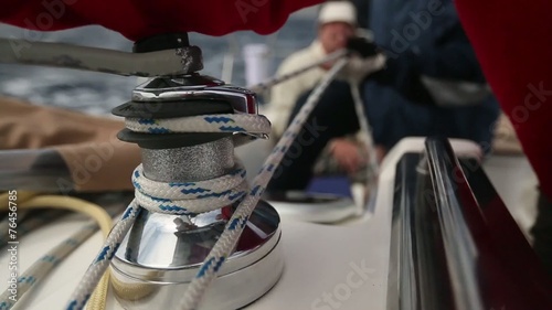 Man pulling ropes, winding sheets around winches.