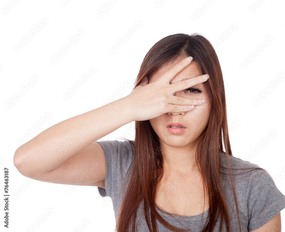 Young Asian woman peeking though her fingers Young Asian woman peeking though her fingers