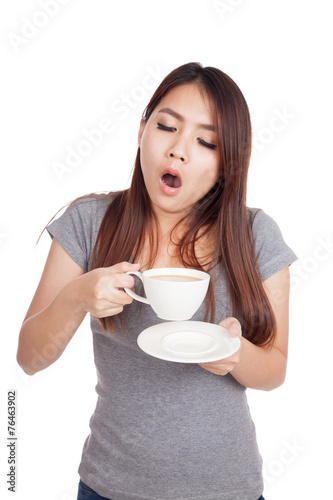 Sleepy young Asian woman yawn with cup of coffee