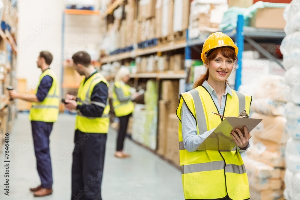 Smiling warehouse manager holding clipboard Smiling warehouse manager holding clipboard
