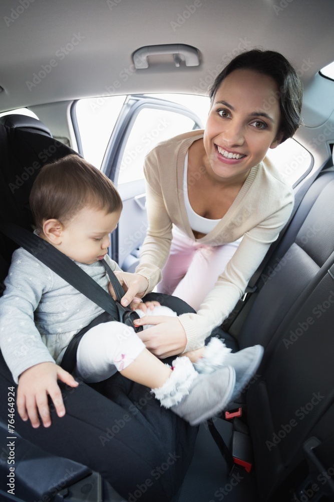 Mother securing her baby in the car seat Mother securing her baby in the car seat
