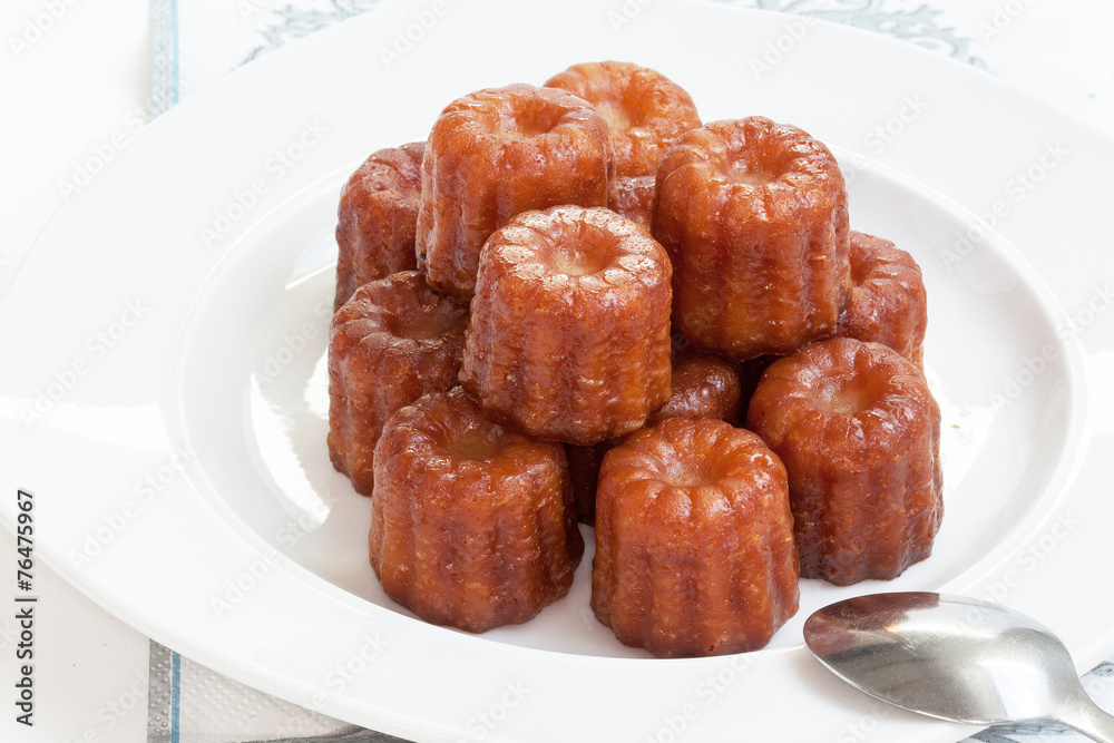 Canelés de Bordeaux empilés sur assiette blanche Canelés de Bordeaux empilés sur assiette blanche