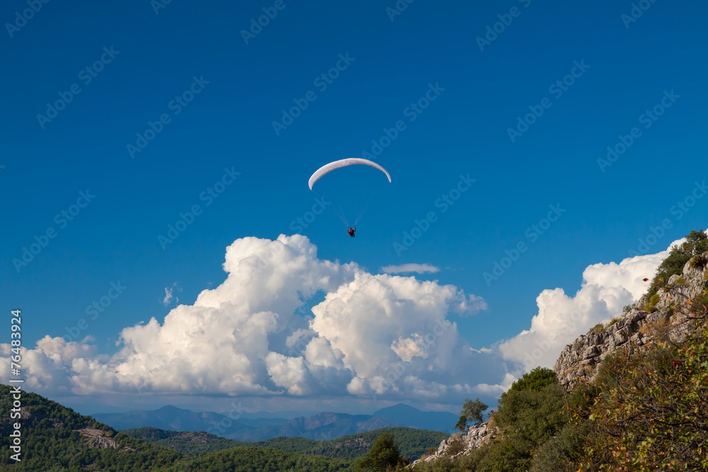 Paraglider flying over sky in summer day