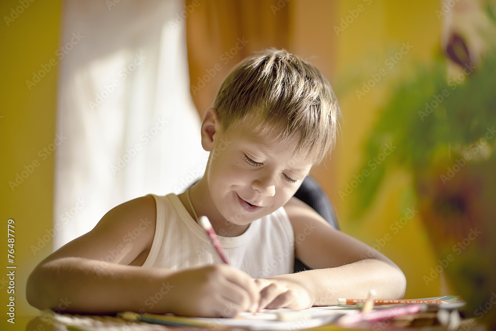 boy at the table draws with crayons