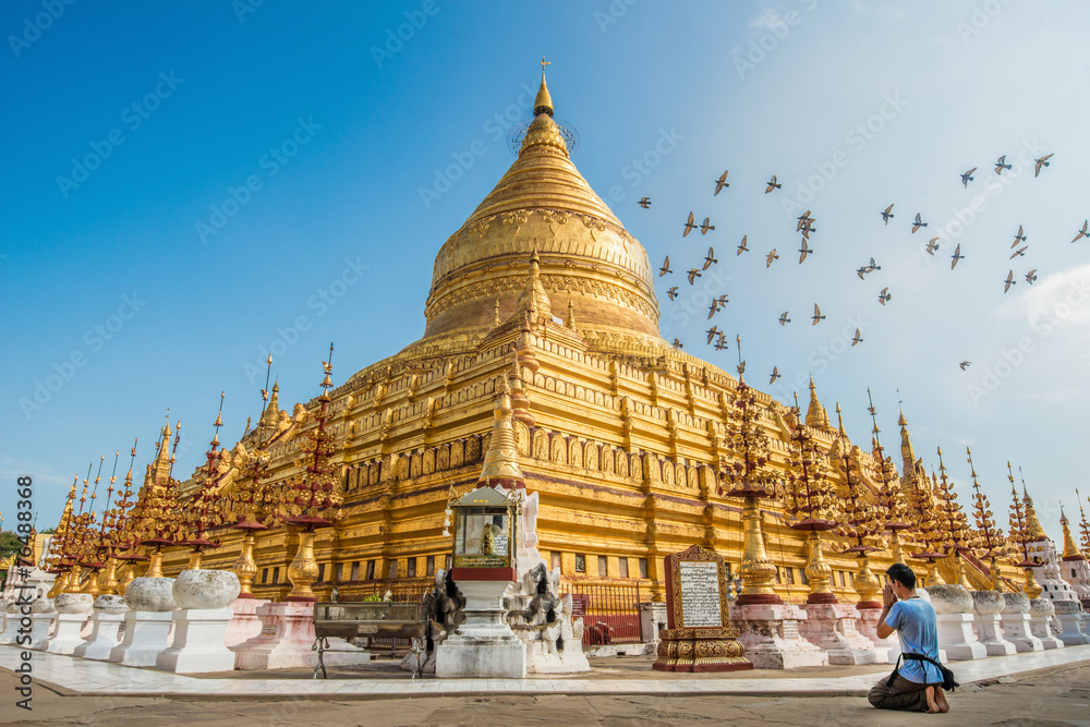 Tourist sitting and praying to Shwezigon pagoda an iconic ancient pagoda in Bagan kingdom of Myanmar.