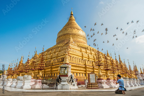 Murais de parede Tourist sitting and praying to Shwezigon pagoda an iconic ancient pagoda in Bagan kingdom of Myanmar