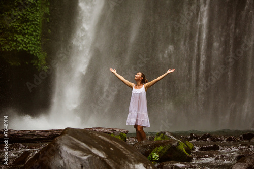 young woman doing yoga in a forest near waterfall