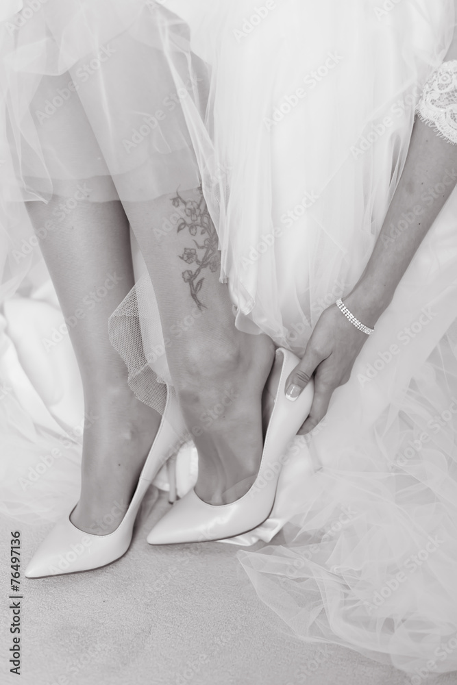 bride is wear on her shoes for the wedding day
