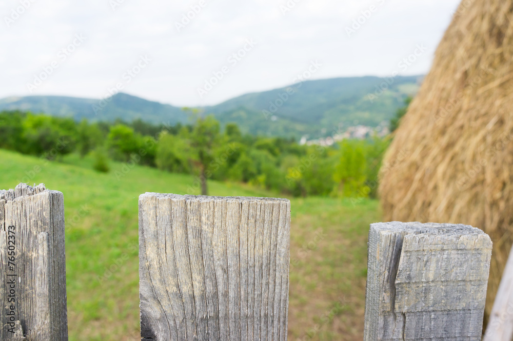 closeup of a fence with garden and hay in the background