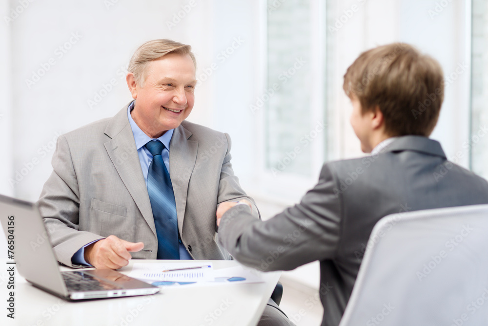 older man and young man shaking hands in office older man and young man shaking hands in office