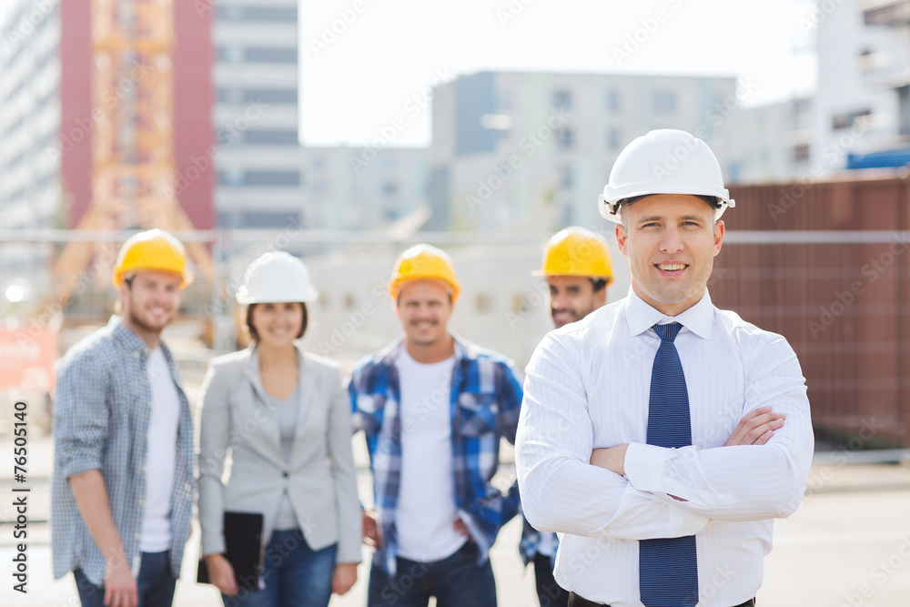 group of smiling builders in hardhats outdoors group of smiling builders in hardhats outdoors
