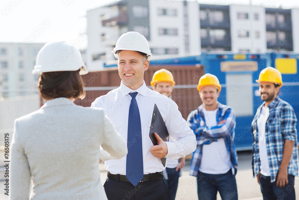 group of smiling builders in hardhats outdoors group of smiling builders in hardhats outdoors