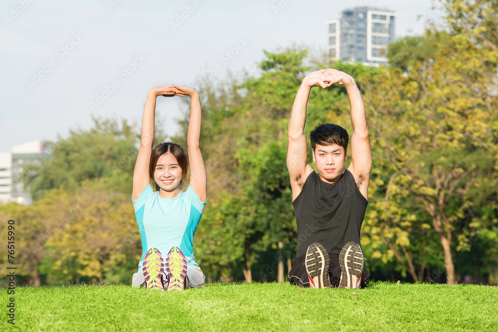 Obraz premium Young couple stretching before exercise together in park