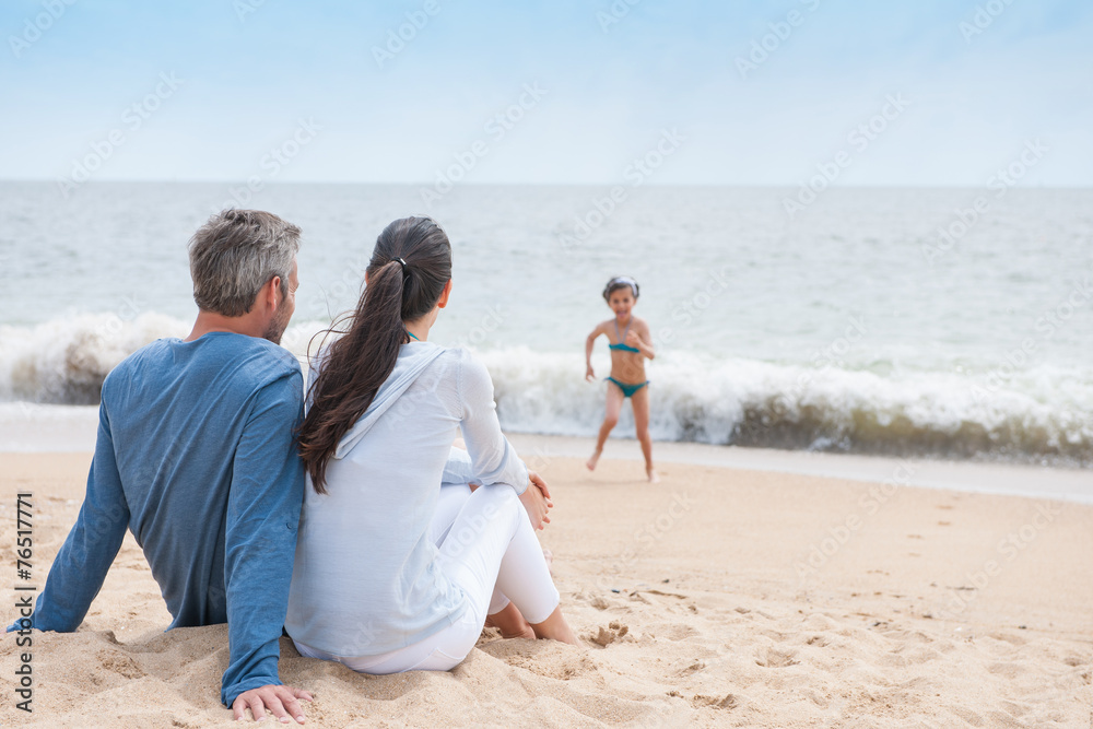 A youg couple is looking at their child while she is playing in A youg couple is looking at their child while she is playing in