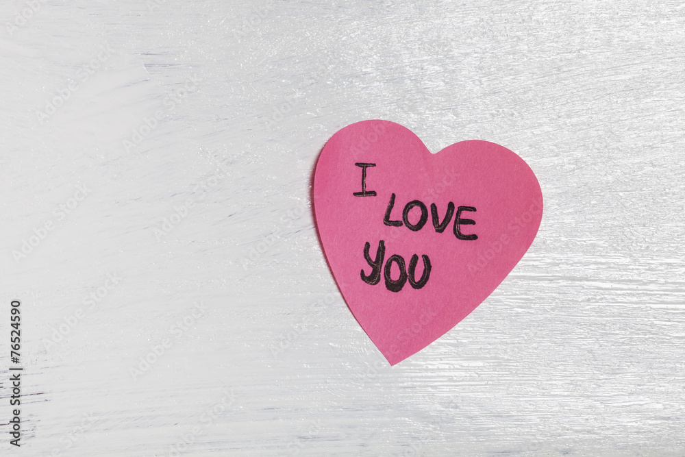 Heart-shaped post-it on the wall with love message Heart-shaped post-it on the wall with love message