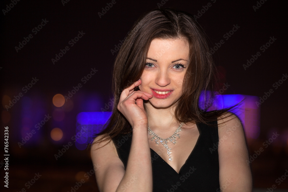 Fototapeta premium Beautiful young woman against night shined city.