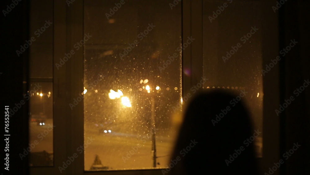 The girl pressed against the window and looking at the first sno