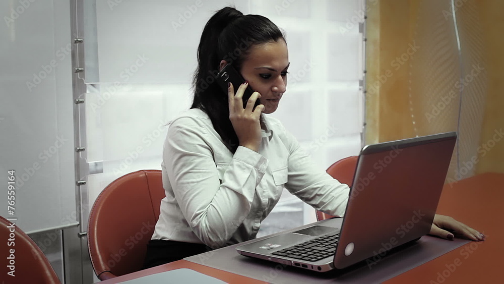 Portrait of a young woman on phone in front of a laptop computer Portrait of a young woman on phone in front of a laptop computer