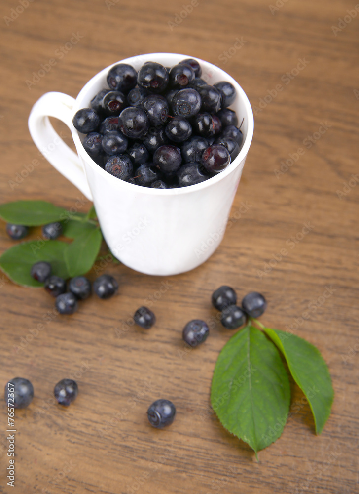 blueberries with leaf in bowl, cup on wooden background blueberries with leaf in bowl, cup on wooden background