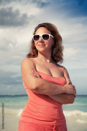 Young smiling woman in red dress on the ocean coast