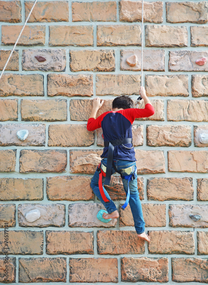 a kid climbs up a wall