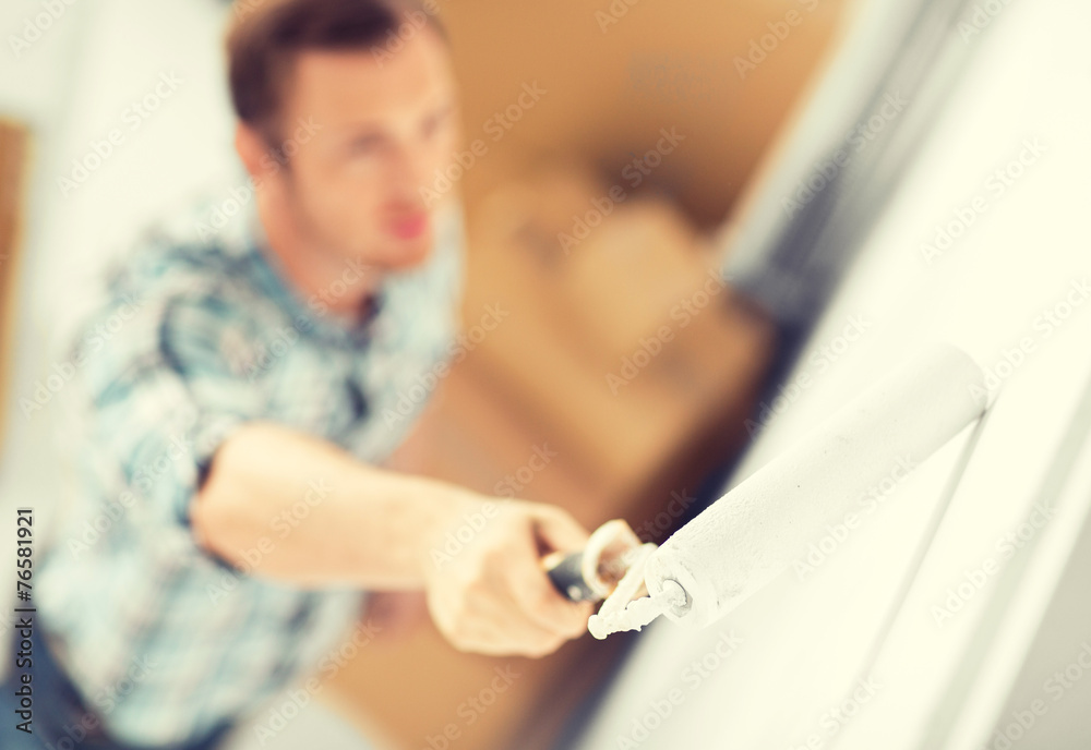 man colouring the wall with roller