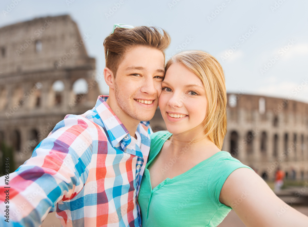 smiling couple taking selfie over coliseum smiling couple taking selfie over coliseum