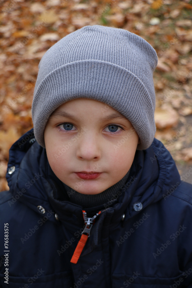 The boy in a cap and jacket for a walk in the park The boy in a cap and jacket for a walk in the park