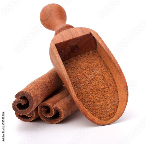 ground cinnamon spice powder in wooden spoon isolated on white b