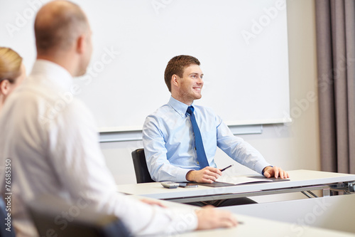 group of smiling businesspeople meeting in office